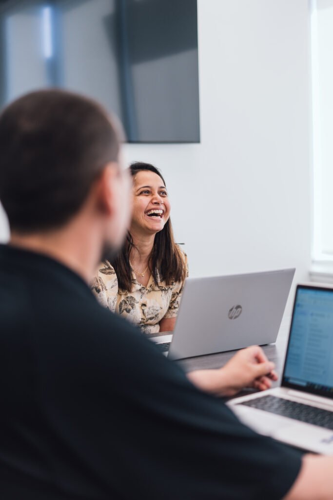Two coworkers laughing at their laptops