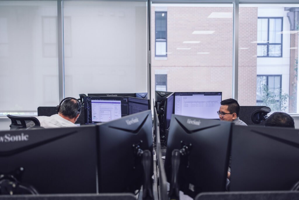Two coworkers sit at their work stations