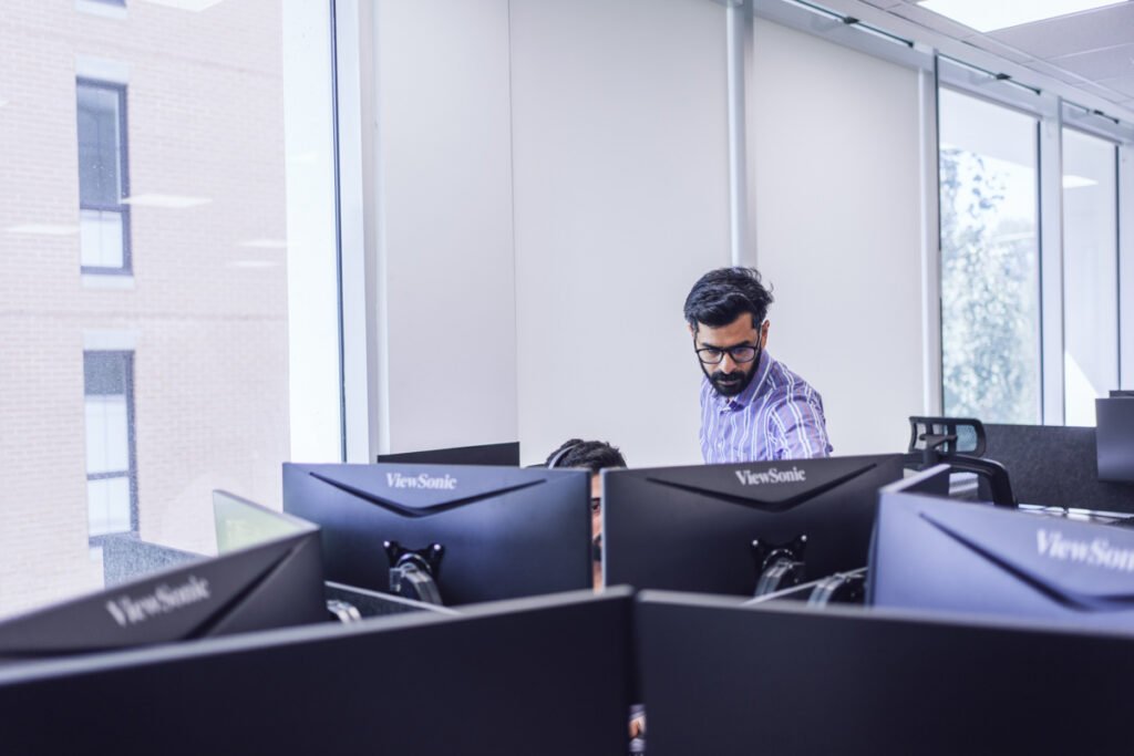 IT manager oversees a colleague at their computer