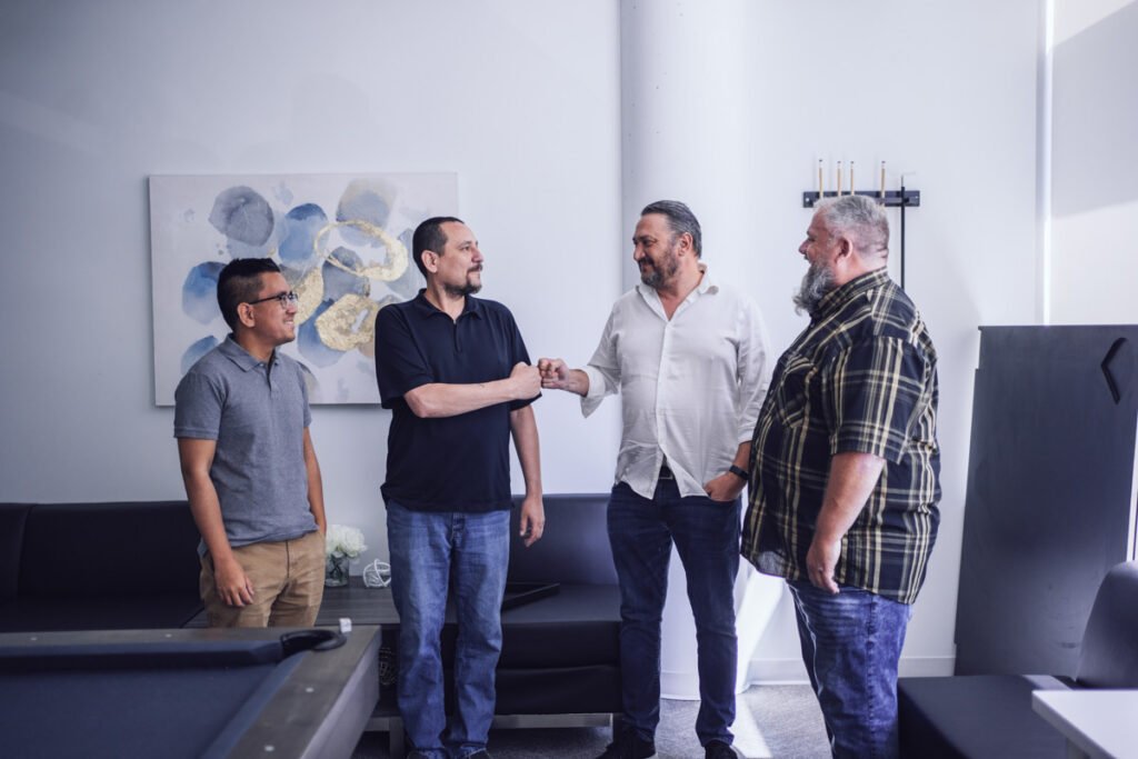 Four coworkers stand chatting in an office